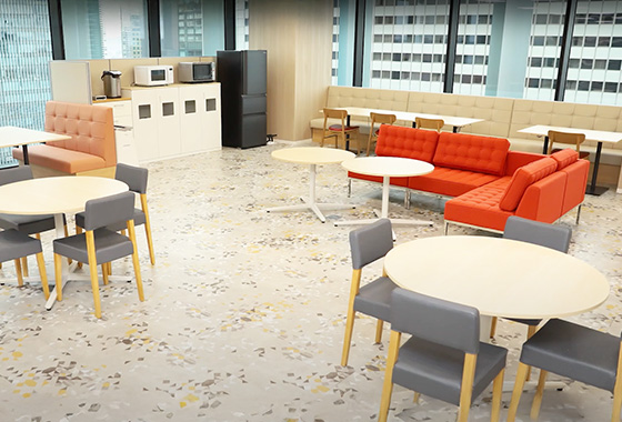 新オフィスの休憩スペース。丸いテーブルとソファ、奥には給湯設備や冷蔵庫を設置している。